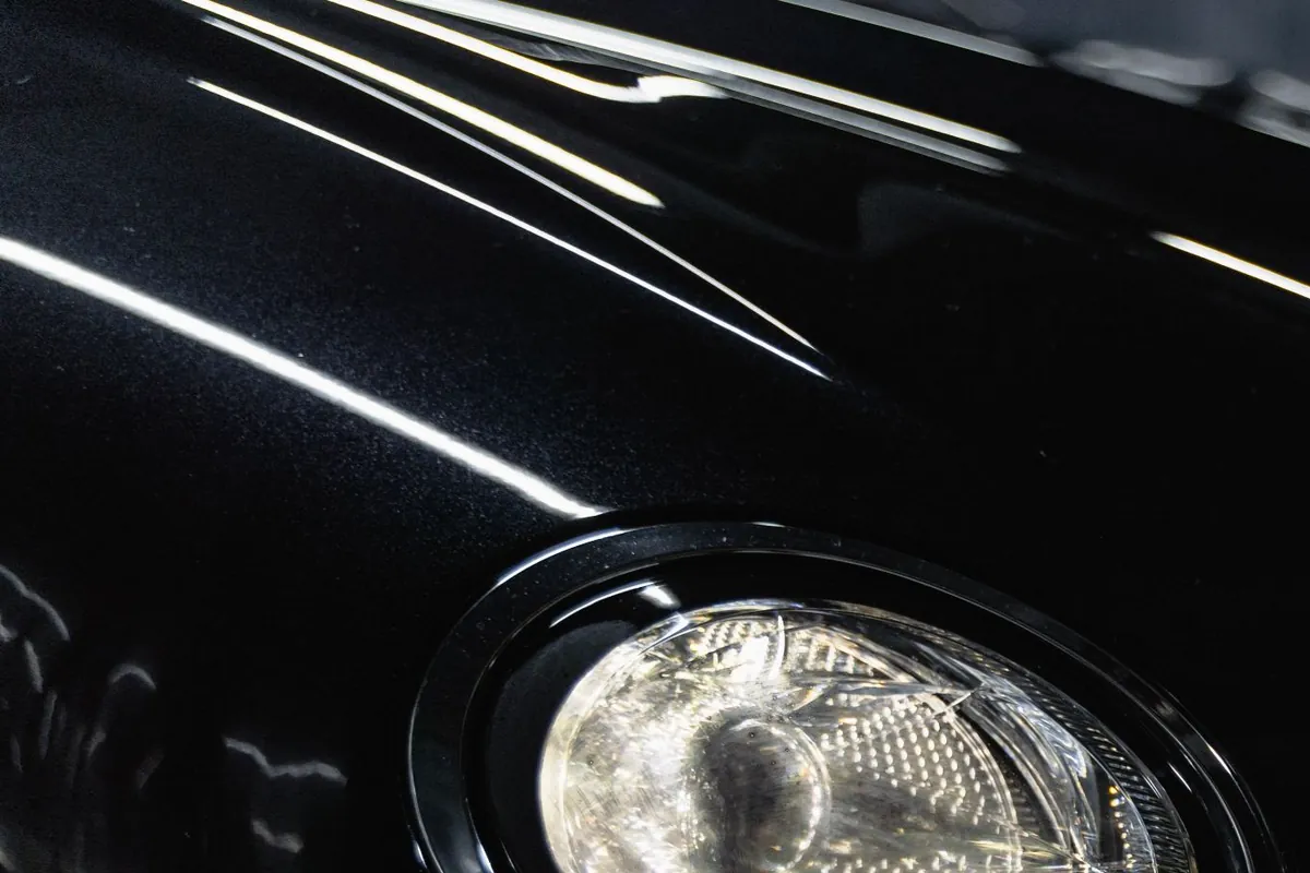 The same black fender after paint correction, a clear mirror finish